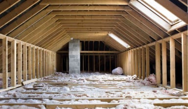 A spacious attic with exposed beams and insulation.