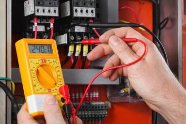 Hand using multimeter to test electrical panel